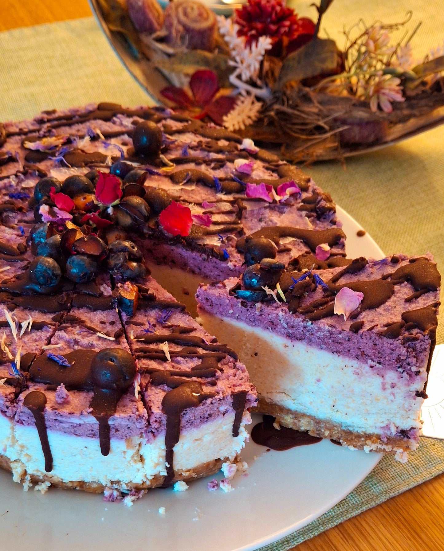 no bake - Blaubeeren-Zitronen-Kokos-Torte im Anschnitt - vegane Torte mit cremiger Textur garniert mit Blaubeeren und Blüten
