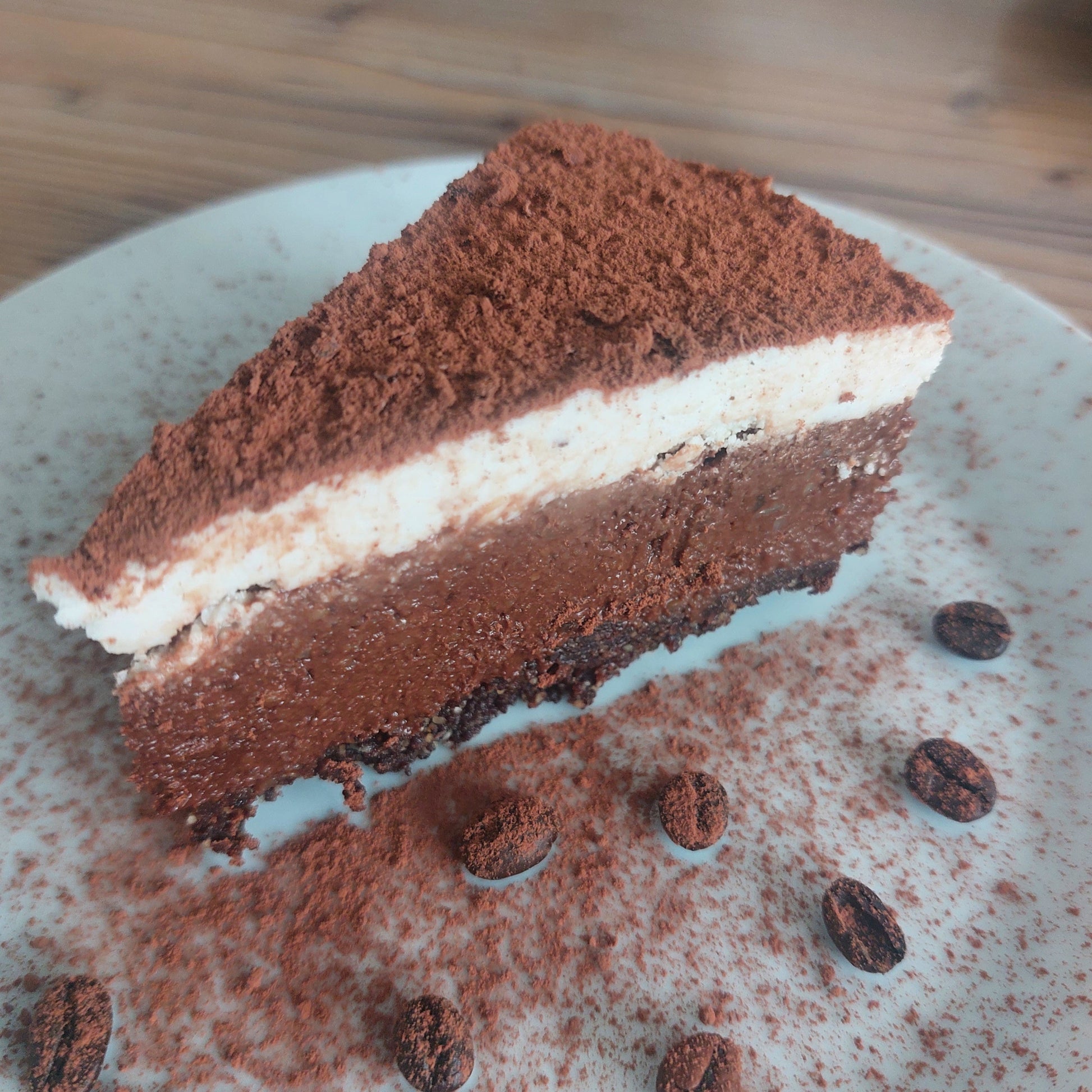 Anschnitt einer veganen Tiraminsu Torte und veganer Macarpone Alternative, bestäubt mit Kakaopulver
